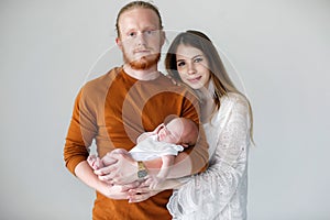 Happy young parents with a newborn son in their arms in the Studio on a white background.