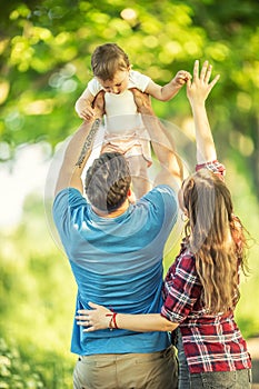 Happy young parrents throws up her little daughter in the park