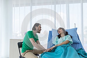 Happy young patient relative with casual clothes is touching and holding female patient's hands. photo
