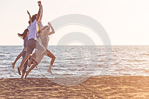 Happy young people group have fun white running and jumping on beach at sunset time