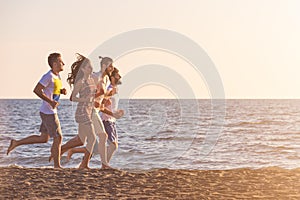 Happy young people group have fun white running and jumping on beach at sunset time