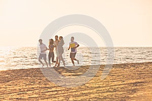 Happy young people group have fun white running and jumping on beach at sunset time