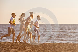 Happy young people group have fun white running and jumping on beach at sunset time