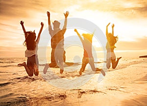 Happy young people jumping on the beach