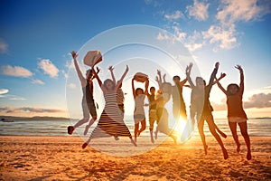 Happy young people jumping at the beach on beautiful sunset