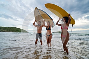 Happy young people with surfboard on the beach.