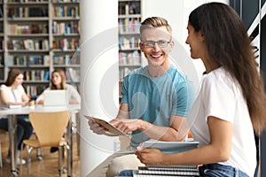 Happy young people talking in library