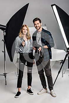 happy young photographers with professional equipment standing together and smiling at camera
