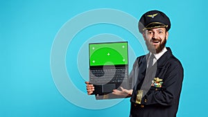 Happy young pilot holding laptop with greenscreen