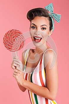 Happy young pin up woman holding candy lollipop.