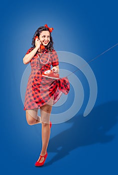 Happy young pinup standing woman talking on phone