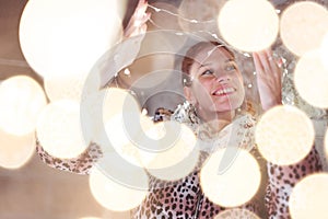Happy young playful 30s woman holding LED garland light outdoors