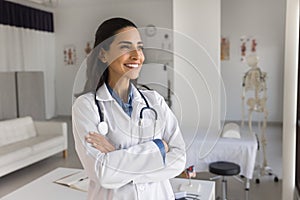 Happy young practitioner doctor posing in medical office