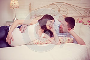 Happy young pregnant couple in bedroom