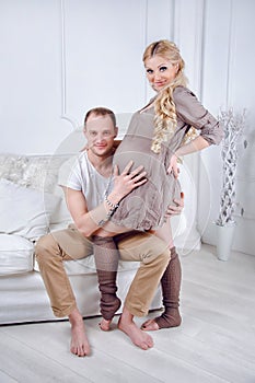 Happy young pregnant couple embrace each other on