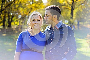 Happy and young pregnant couple hugging in nature