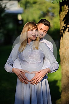 Happy and young pregnant couple hugging outdoor