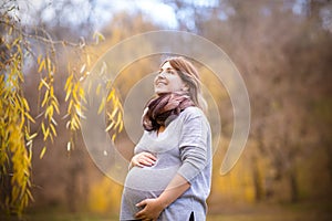 Happy young pregnant woman in autumn park