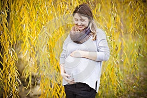 Happy young pregnant woman in autumn park