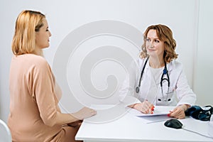 Happy young pregnant woman with blonde hair visiting doctor in prenatal clinic.