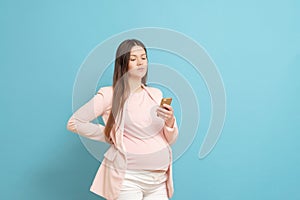 happy young pregnant woman on blue background calls by mobile phone, discharge of amniotic fluid, the beginning of labor process