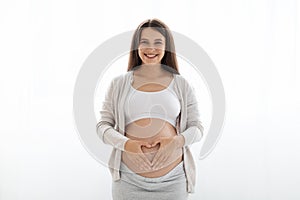 Happy young pregnant woman holding hands on big belly