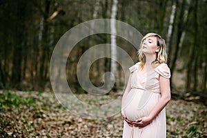 Happy young pregnant woman relaxed in the park