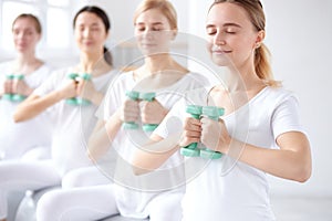 Happy young pregnant women working out with dumbbells on fitball in studio