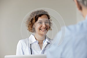 Happy young pretty female general practitioner listening to patient.