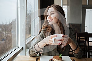 Happy young pretty lady sitting in cafe drinking tea.