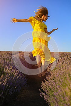 Happy young pretty woman jumps from happiness at sunset in a lavender field. The concept of freedom and positive