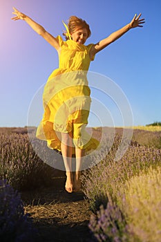 Happy young pretty woman jumps from happiness at sunset in a lavender field. The concept of freedom and positive