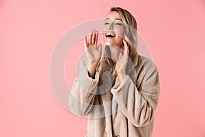 Happy young pretty woman posing isolated over pink wall background screaming loud call out