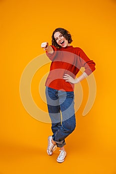 Happy young pretty woman posing isolated over yellow wall background