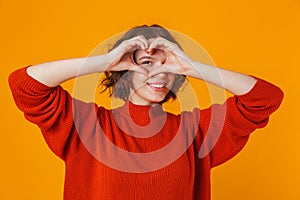 Happy young pretty woman posing isolated over yellow wall background showing heart gesture