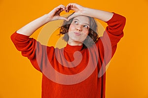 Happy young pretty woman posing isolated over yellow wall background showing heart gesture