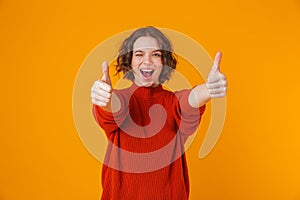 Happy young pretty woman posing isolated over yellow wall background showing thumbs up