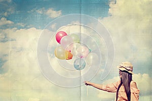 Happy young red hair woman holding colorful balloons and flying on clouds sky background.