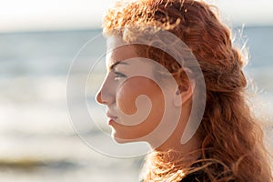 Happy young redhead woman face on beach