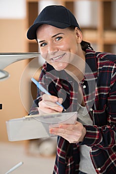 happy young repairwoman with clipboard smiling at camera