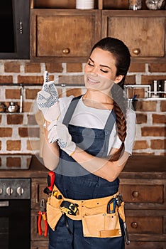 happy young repairwoman putting on work gloves