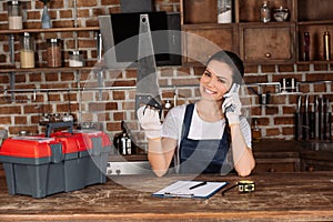 happy young repairwoman with saw taking by phone