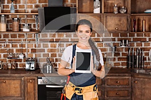happy young repairwoman standing at kitchen