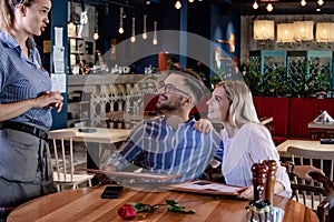 Young romantic couple ordering dinner together in a restaurant.