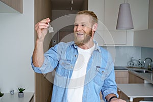 Happy young man renter first time home owner holding key to new apartment