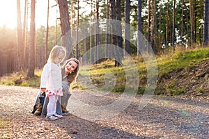 Happy young single mother taking a walk in a park with her toddler daughter. Family smiling and having fun