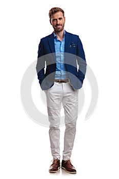 Happy young smart casual man standing with hands in pockets