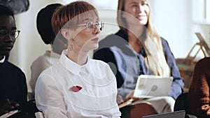 Happy young smart Caucasian business woman asking questions at corporate seminar during modern office conference.