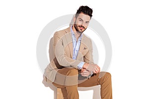 Happy young smartcasual man sitting and fixing sleeve