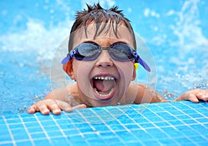 Happy young smiling boy in the swimming pool